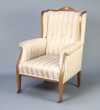 An Edwardian inlaid mahogany winged armchair upholstered in Regency stripe material 