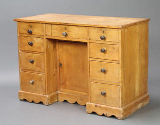 A Victorian pine pedestal dressing table/desk fitted a drawer above a cupboard enclosed by a panelled door and flanked by 8 short drawers with tore handles, raised on bracket feet 76cm h x 110cm w x 51cm d 