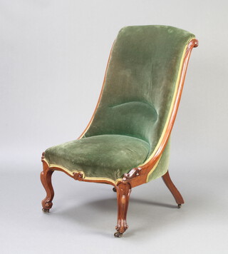 An early Victorian mahogany show frame nursing chair upholstered in green material, raised on cabriole supports brass caps and casters 