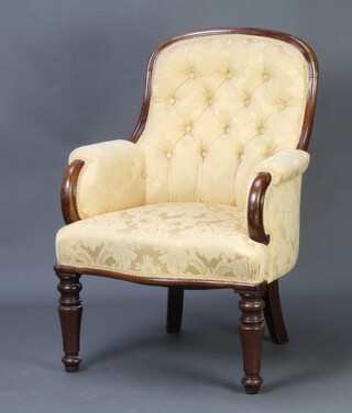 A Victorian mahogany show frame armchair upholstered in yellow buttoned material, raised on turned supports 