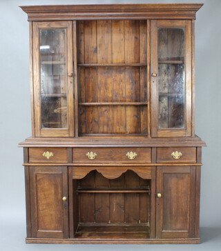 A Victorian oak dog kennel dresser, the upper section with moulded cornice fitted 2 shelves flanked by a pair a cupboards, the base fitted shelves above 1 long and 2 short drawers with a recess flanked by cupboards 202cm h x 153cm w x 47cm d 