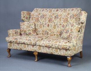 A Queen Anne style wing back 2 seat sofa upholstered in tapestry material, raised on cabriole supports 95cm h x 152cm w x 66cm d 