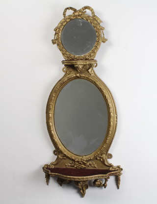 A Victorian arched plate mirror contained in a painted gilt frame, upper section with circular plate mirror with garlands and shelf, the base with oval mirror above a shelf decorated musical trophies 80cm h x 35cm w 