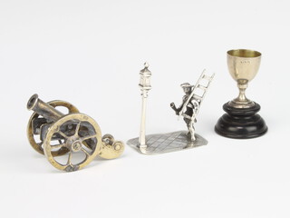 A miniature silver figure of a lamp lighter, a cannon and a cup 56 grams