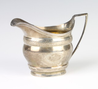 A George III cream jug with engraved decoration and vacant armorial London 1803, 164 grams 