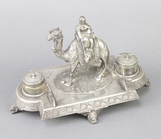 A Victorian ex-plated ink stand with a figure riding a camel and having 2 lidded inkwells and a pen rack on scroll feet 24cm 