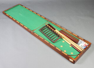 A W Gamages of Holborn London, a table top bagatelle game with 4 cues, 4 white balls, 4 red balls and 1 black ball, 2 scoring markers, contained in a mahogany folding case 12cm h x 182cm l x 45cm w 