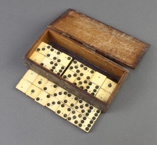 A set of 28, 19th Century bone and ebony dominoes, contained in a wooden box with hinged lid which has replacement hinges  