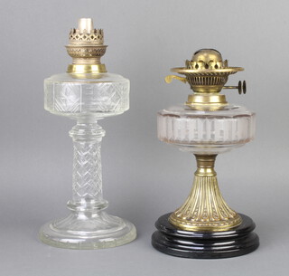 A Victorian faceted glass oil lamp reservoir raised on an embossed gilt metal base with ceramic socle base 28cm x 15cm, together with an engraved cut glass ditto 26cm x 17cm  
