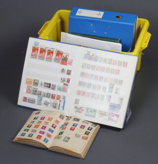 4 albums of world stamps and stock books contained in a yellow plastic crate 
