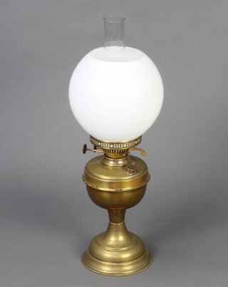 A gilt metal oil lamp with clear glass chimney and opaque shade 53cm h x 14cm diam.