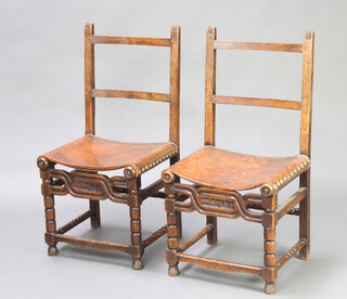 A pair of 17th Century style oak ladder back chairs with leather seats, carved and pierced aprons, raised on bobbin turned and block supports 