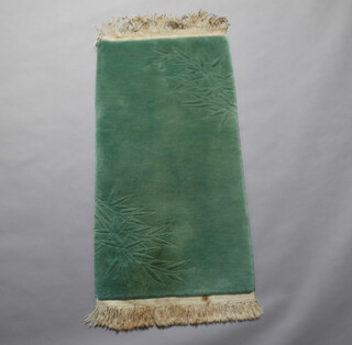 A sculpted green ground Chinese rug with blue decoration 129cm x 64cm (some staining in places) 