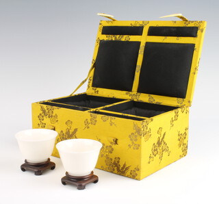 A pair of Chinese white glazed 18th Century style tea bowls with flared rims 4cm on hardwood stands in a fitted case (one bowl has a small chip to the rim) 