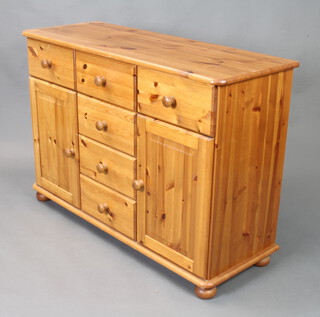 A pine dresser base fitted 6 drawers flanked by cupboards, raised on bun feet with tore handles 82cm h x 117cm w x 43cm d 