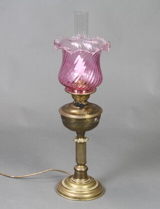 A Victorian style gilt metal oil lamp with clear glass chimney and red glass shade (converted to a table lamp) 70cm x 17cm 
