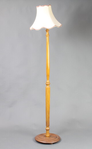 A turned beech standard lamp raised on a circular base 142cm h x 34cm diam. 