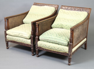 An Edwardian mahogany show frame double cane 3 piece bergere suite - 3 seat settee and 2 armchairs, upholstered in green and floral material (some damage to the caning and staining to the upholstery) 
