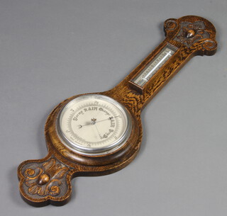 An aneroid barometer and thermometer with silvered dial, contained in a carved oak case 