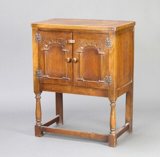 An oak cabinet enclosed by arched panelled doors on turned and block supports 73cm h x 56cm w x 32cm d (ring mark and water damage to the top) 