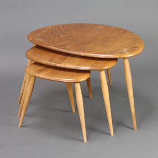 Ercol, a nest of 3 light elm Pebble interfitting coffee tables raised on turned supports 39cm h x 64cm w x 42cm d, 35cm x 49cm x 35cm and 31cm x 33cm x 23cm (largest and middle table have water marks and scratches and there are slight scratches to the smallest table) 