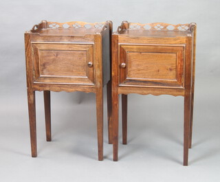 A pair of Georgian style mahogany night tables with pierced gallery enclosed by panelled doors, raised on square tapered supports 75cm h x 44cm w x 36cm d 