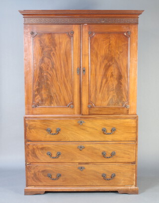A Georgian mahogany linen press secretaire, the upper section with moulded and dentil cornice, blind fretwork frieze above cupboard with 5 trays enclosed by panelled doors, the base with well fitted secretaire drawer above 2 drawers, raised on a platform base 198cm h x 129cm w x 62cm d  