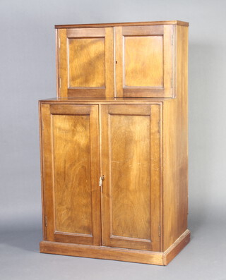 An Edwardian Art Nouveau mahogany cabinet on cabinet, both sections with cupboards enclosed by panelled doors, raised on a platform base 149cm h x 84cm w x 21cm d 