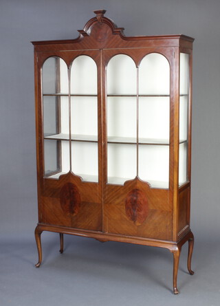 An Edwardian shaped mahogany display cabinet, the upper section with arched top, fitted shelves enclosed by astragal glazed panelled doors, raised on cabriole supports 205cm h x 122cm w x 37cm d 