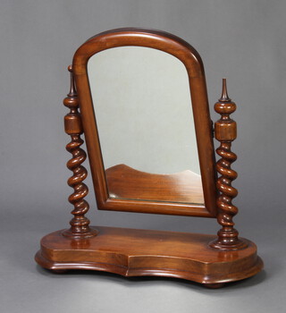 A Victorian arched plate dressing table mirror contained in a mahogany swing frame raised on spiral turned columns and having a shaped base raised on bun feet 56cm x 57cm w x 26cm d 