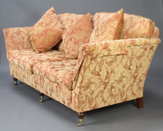 A Victorian style 2 seat sofa upholstered in floral patterned material raised on turned feet, brass caps and casters 87cm h x 205cm w x 92cm d together with a matching armchair 87cm h x 92cm w x 79cm d and footstool 30cm x 73cm x 52cm (stains to the top of the stool) 