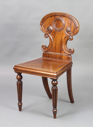 A Georgian mahogany hall chair with shaped back and solid seat raised on turned and reeded supports 