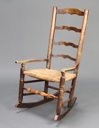 An 18th Century elm ladder back rocking armchair with woven rush seat 