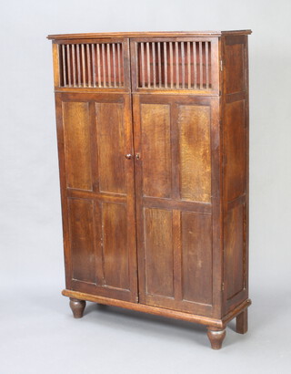 An 18th Century Continental oak food cabinet with shelved interior enclosed by a panelled and grilled door, raised on turned supports 149cm h x 96cm h x 34cm d (made up) 
