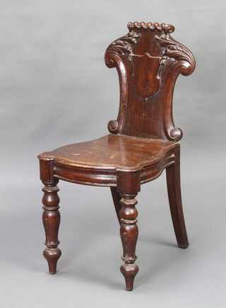 A Victorian carved oak hall chair with shield shaped back and solid seat, raised on turned and fluted supports