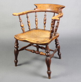 A 19th Century elm smokers bow chair with spindle decoration and solid seat, raised on turned supports with double H framed stretcher