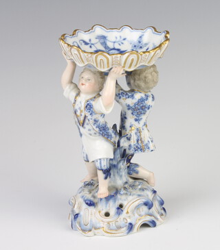 A 19th Century German blue and white table salt in the form of 2 young men holding aloft a bowl decorated with flowers, raised on a Rococo base with applied flowers 14cm 
