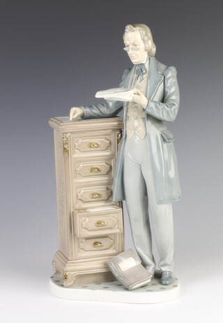 A Lladro figure of a gentleman standing beside a 5 drawer chest 34cm 