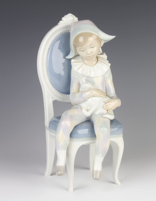A Lladro figure of a seated Pierrot child holding a cat 25cm 