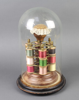 A Victorian cylindrical gilt metal 3 and beech tier 18 division cotton reel stand, the top incorporating a pin cushion and contained under a glass dome 36cm h x 22cm diam. 
