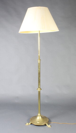 An Art Nouveau brass adjustable standard lamp raised on a circular base with panel feet 