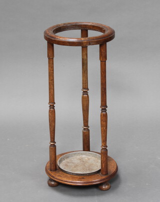 A 1930's circular oak stick/umbrella stand complete with drip tray, on bun feet 62cm h x 26cm w (old repaired break to the top) 