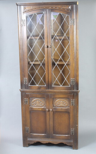 An oak double corner cabinet, upper section fitted fitteds enclosed by lead glazed panelled doors, the base enclosed by panelled doors 167cm h x 67cm w x 46cm d (section of cornice missing to the top) 
