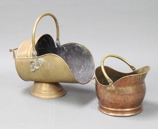 A brass helmet shaped coal scuttle on a circular foot 26cm h x 54cm x 27cm together with a copper and brass ditto 25cm h x 30cm x 26cm 