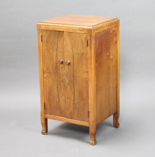 A 1940/50's bleached walnut sheet music cabinet fitted shelves enclosed by panelled doors, raised on square supports 76cm h x 41cm w x 36cm d (some sun bleaching and water marks)