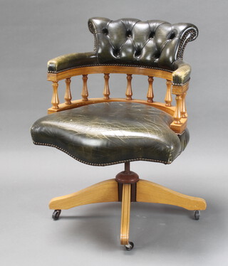 A beech framed revolving office chair upholstered in green buttoned leather (some cracking to leather, bald patch to the arm)