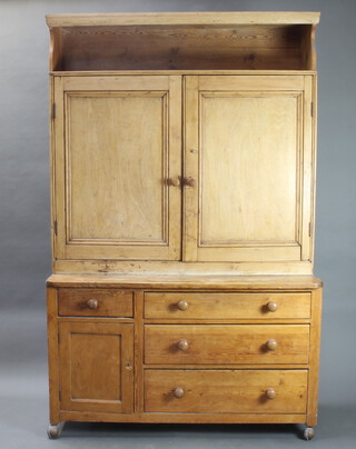 A pine dresser, the upper section with recess above cupboard enclosed by arched panelled doors, base fitted 3 drawers flanked by 1 short drawer and cupboard 202cm h x 128cm w x 49cm d (made up) 