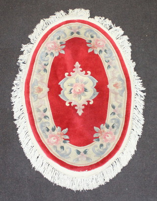 An oval red and white floral patterned Indian rug 131cm x 323cm (some staining and pulling in places)
