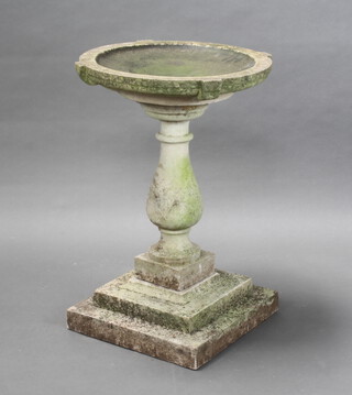 A circular reconstituted stone bird bath raised on baluster column and stepped base 76cm h x 53cm diam. (the column has 2 chips at the top, a crack to the centre and does not sit well on the stepped base) 