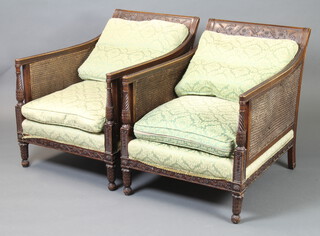 A pair of Edwardian mahogany show frame double cane armchairs, upholstered in green and floral material (some staining to the upholstery) 